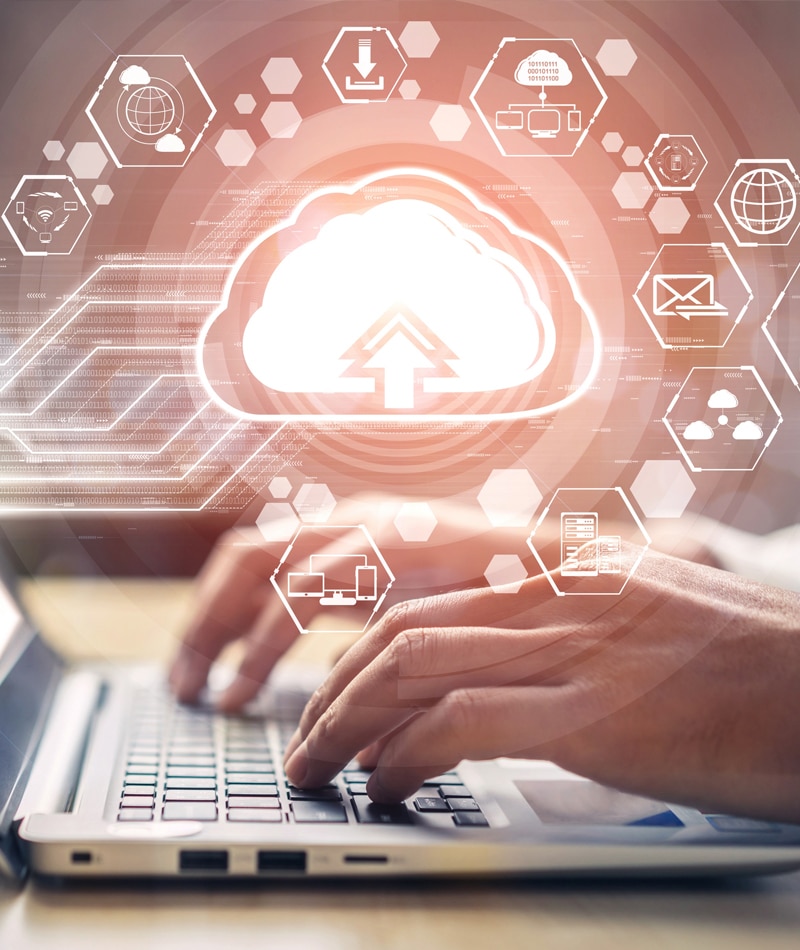 A glowing cloud above hands typing on a keyboard, signifying cloud computing services.