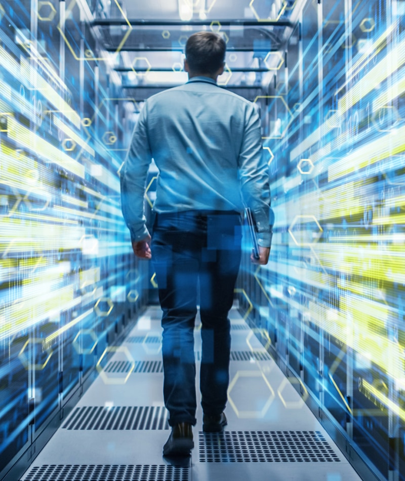 A man walking down a row of servers, representing managed IT services in Cypress.