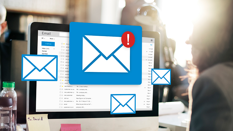 An email icon signaling a full inbox in front of a computer screen.