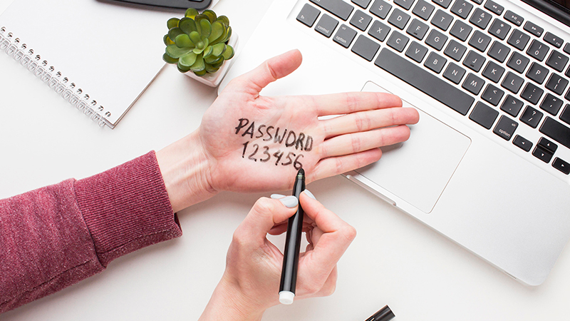 A person writing the insecure password "123456" on their hand in sharpie.