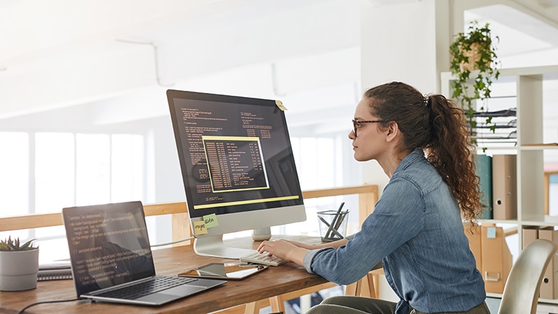 A woman sitting in front of her computer working on a tech project.