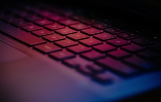 Close up of a keyboard illuminated with pink and purple light