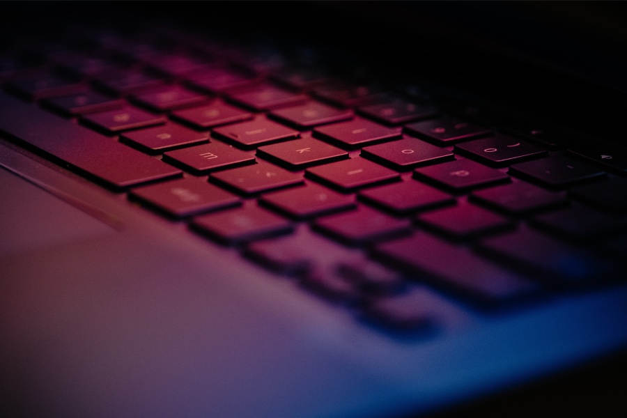 Close up of a keyboard illuminated with pink and purple light