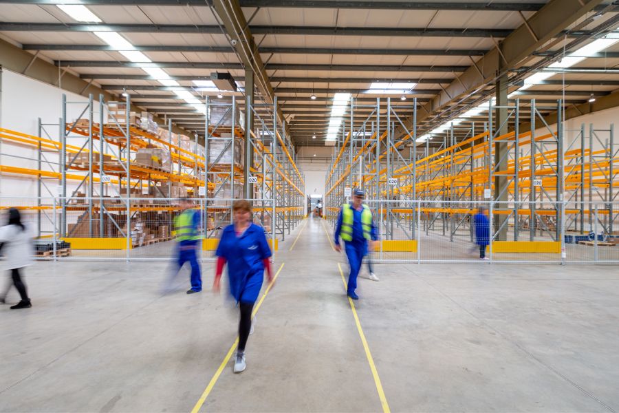 the inside of a warehouse with workers walking around