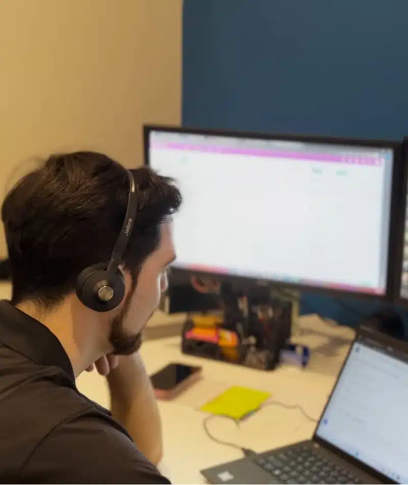 Close up of an IT support specialist managing a laptop, tablet, and monitoring systems.